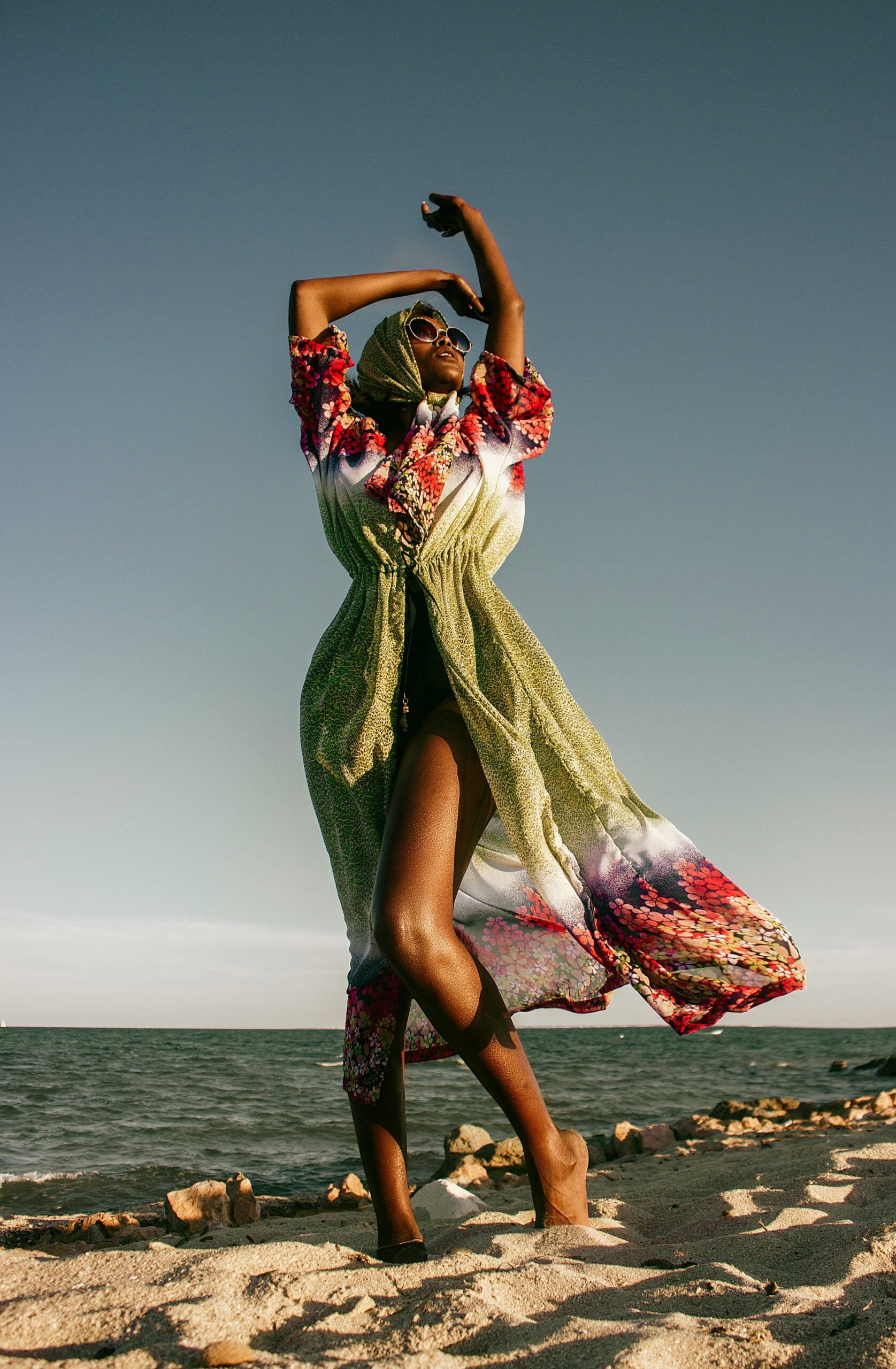 a woman dancing on the beach in a dress